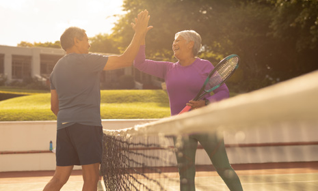 Two people playing tennis and high‑fiving